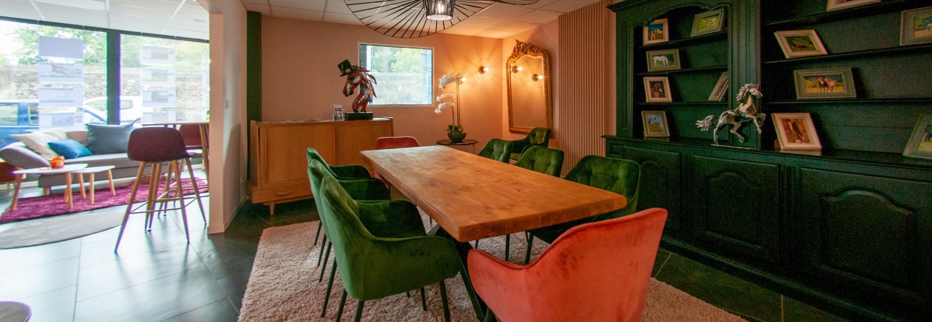 Joli salle à manger, avec une table en bois, de jolis sièges vert et orange mettant le meuble de derrière en valeur